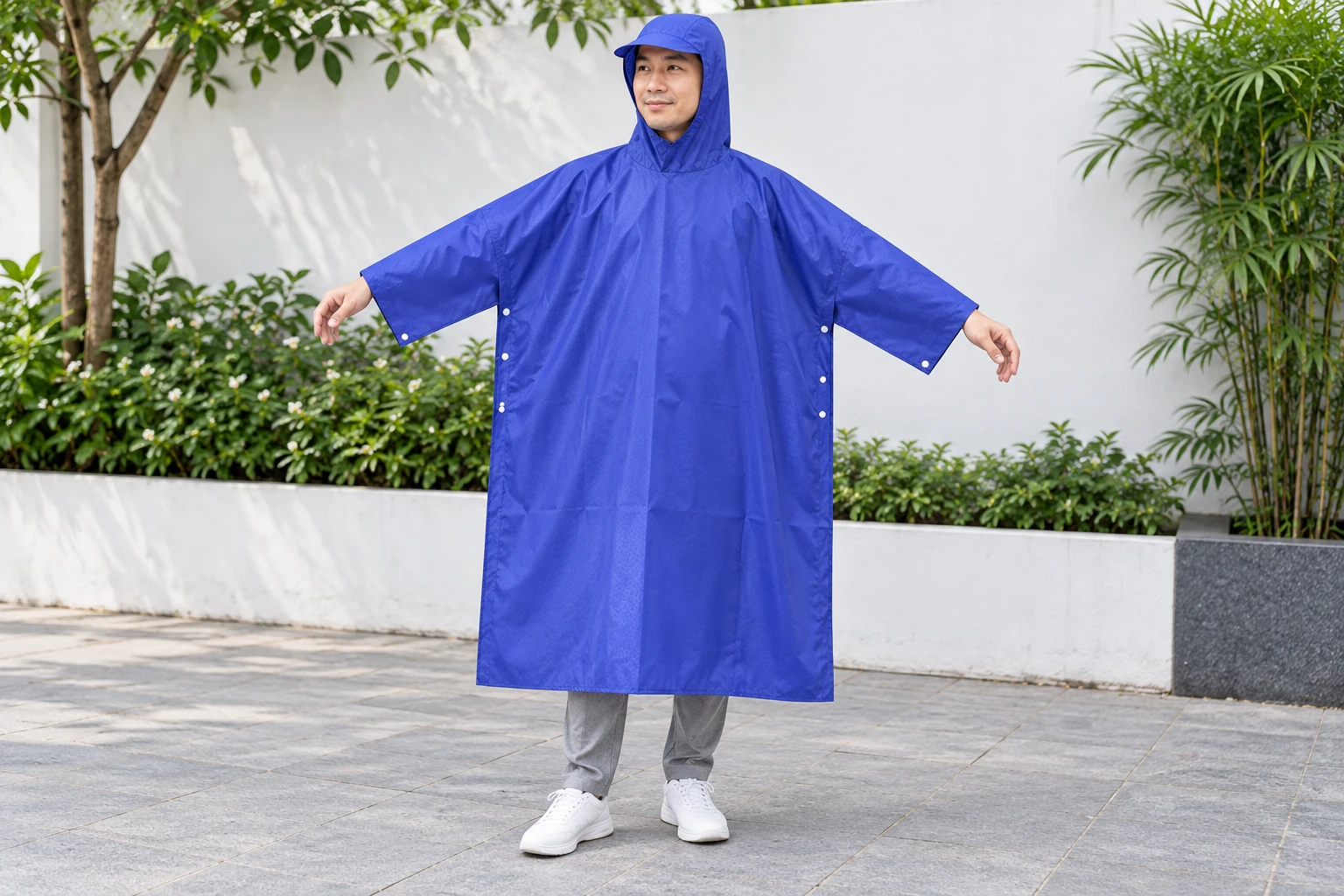 Người mặc thử áo mưa có tay màu xanh khi đứng ở sân khô