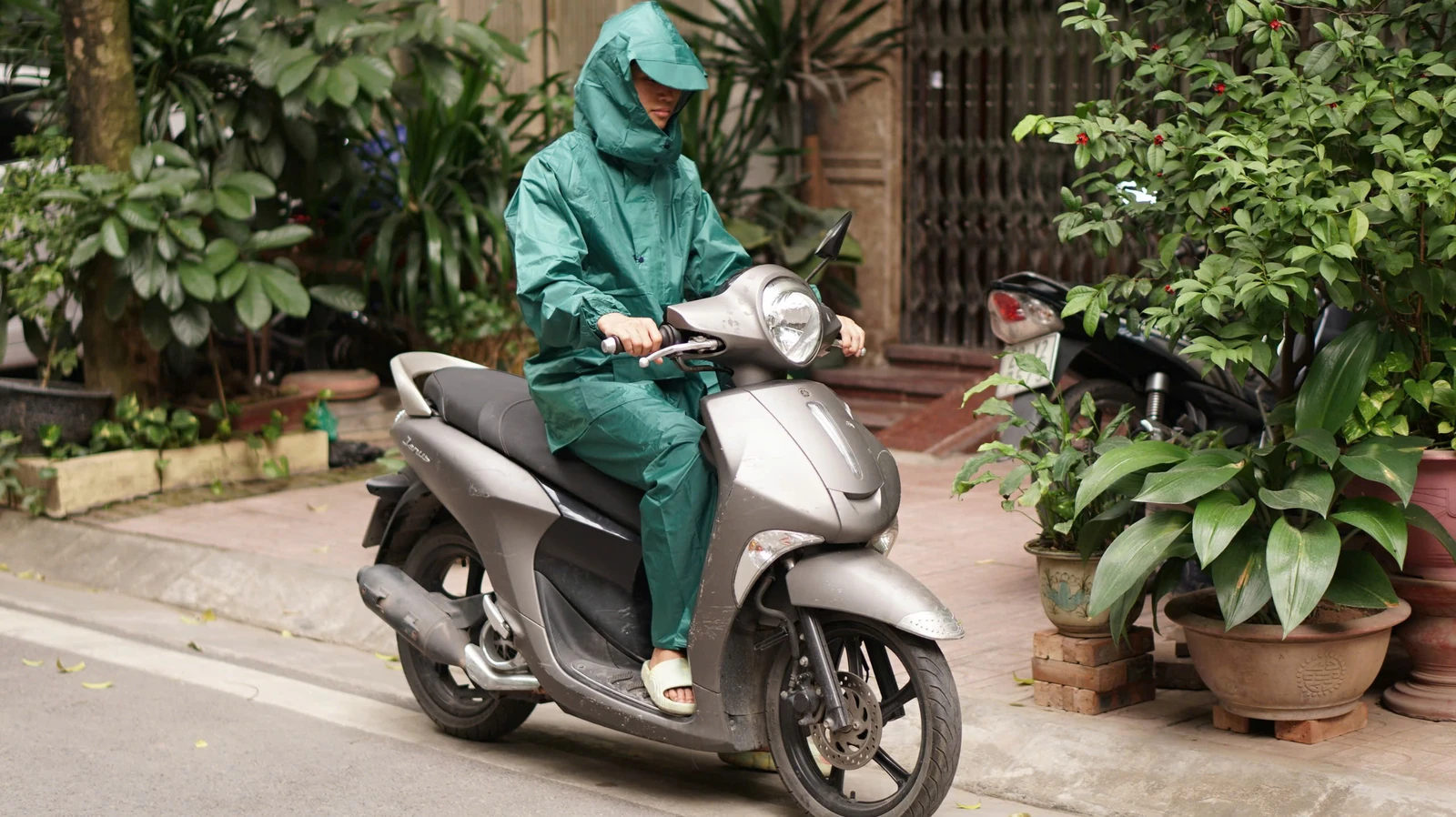 Mẫu bộ áo mưa xanh ngọc ở tư thế ngồi nhìn từ phía trước chếch bên