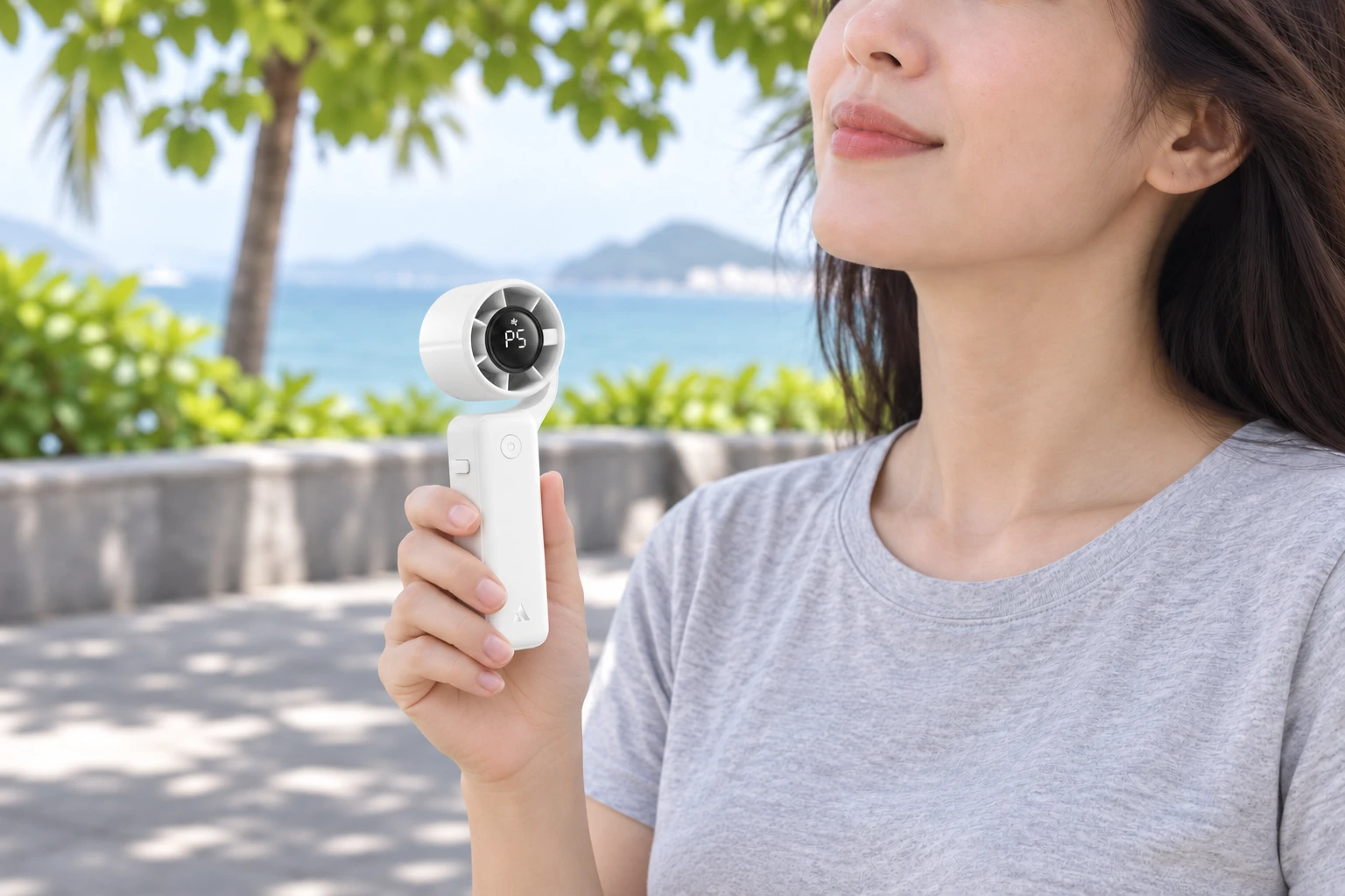 Người dùng cầm quạt AECOOLY PF04 trắng khi nghỉ trên lối đi có bóng râm